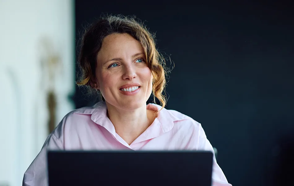 Leende person framför en laptop.